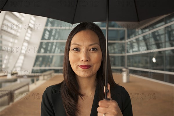 Asian businesswoman underneath umbrella