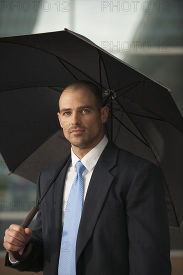 Caucasian businessman underneath umbrella