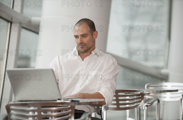Caucasian man using laptop in cafe