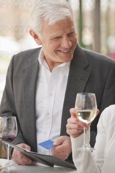 Caucasian couple drinking wine and paying bill