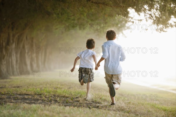 Caucasian boys running in orchard