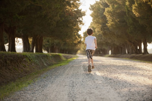 Caucasian boy running on dirt road