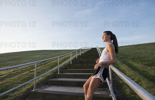 Caucasian runner leaning on staircase railing