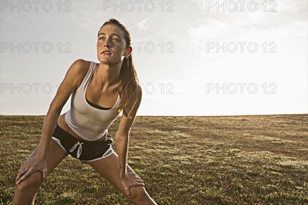 Caucasian runner stretching in field