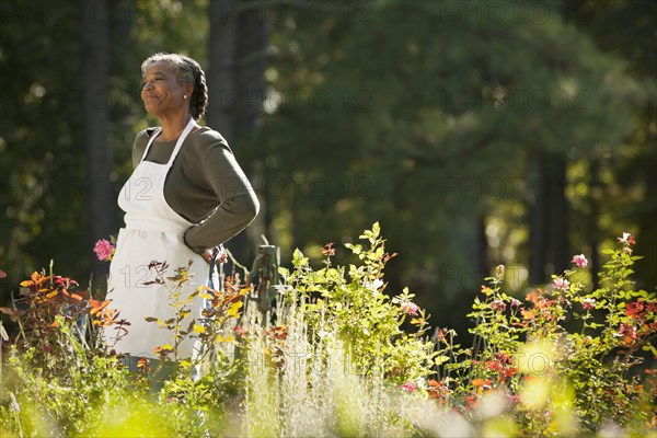 Mixed race woman wearing apron in field