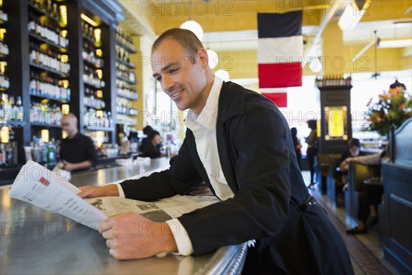 Caucasian man reading newspaper in cafe