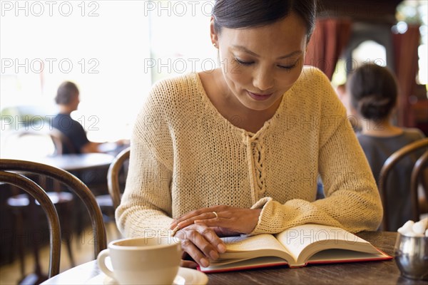 Filipino woman reading book in cafe