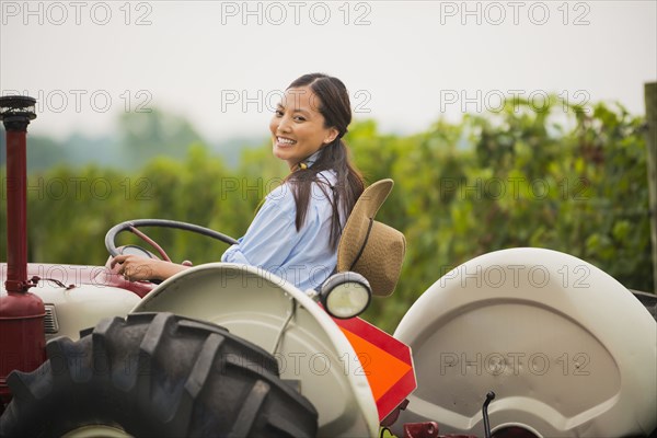 Asian woman driving tractor in field