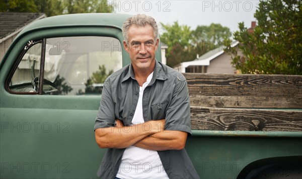 Caucasian farmer leaning against truck outdoors
