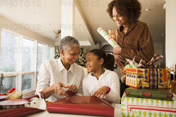 Three generations of women wrapping Christmas presents