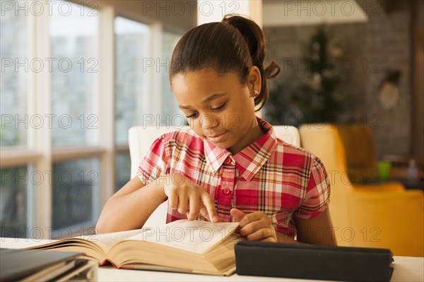 African American girl reading at table