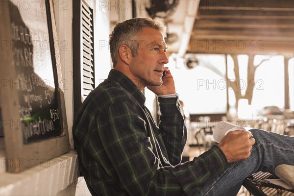 Caucasian man talking on cell phone on patio