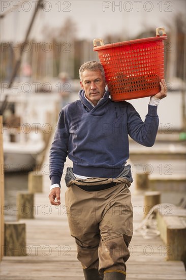 Caucasian fisherman carrying basket on dock