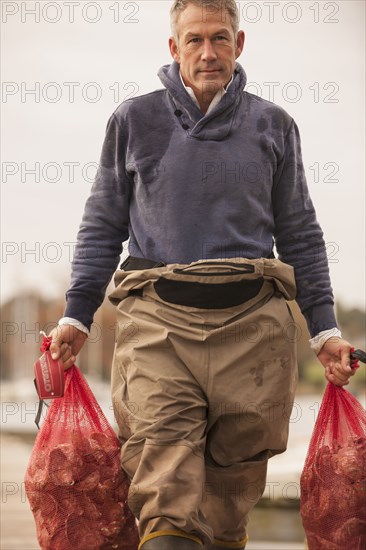 Caucasian fisherman carrying catch on dock