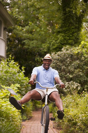 African American man riding bicycle in backyard