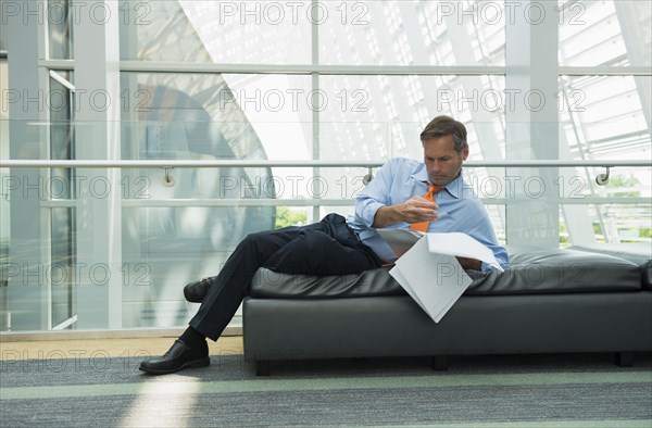 Caucasian businessman reading in lobby area