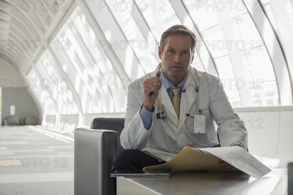 Caucasian doctor reading in lobby area