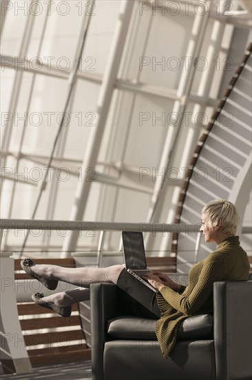 Caucasian businesswoman using laptop in lobby