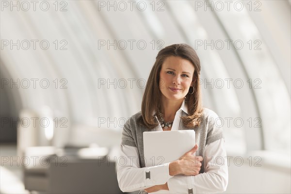 Caucasian businesswoman carrying papers in lobby