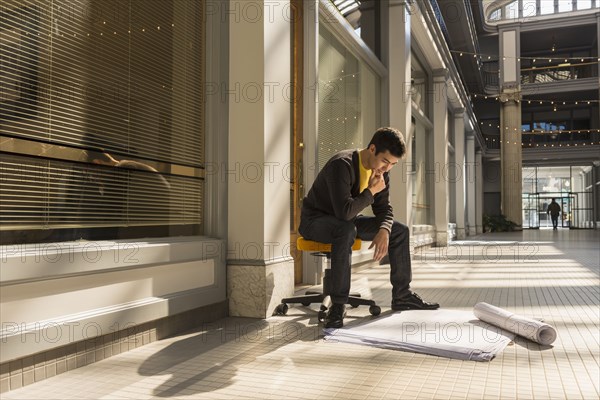 Mixed race man reading blueprints in building