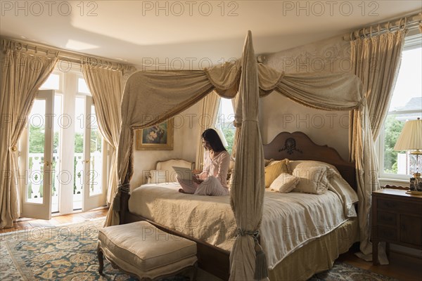 Hispanic woman using laptop on bed