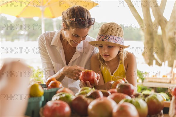 Mixed race mother and daughter browsing produce at farmers market