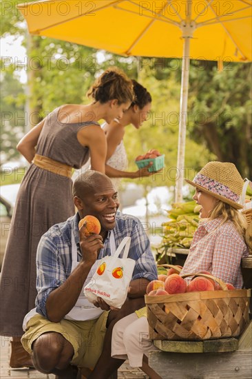 Vendor showing produce to girl at farmers market