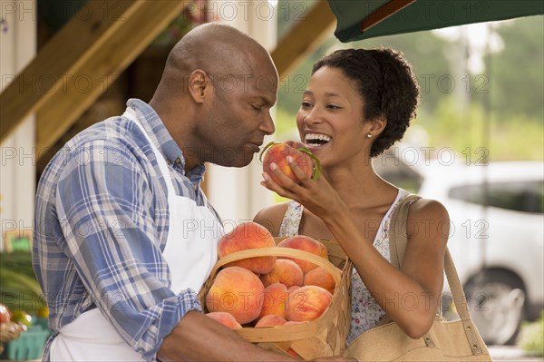 African American people smelling produce at farmers market