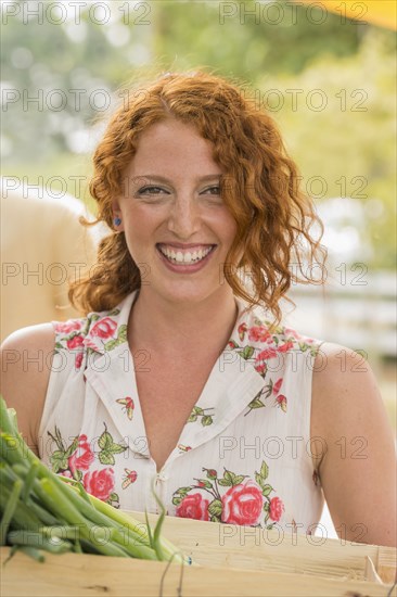 Caucasian woman carrying crate of produce