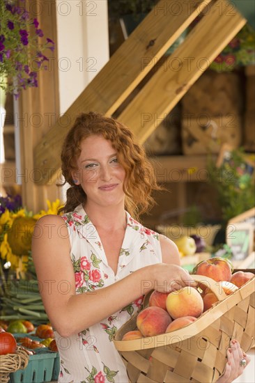 Caucasian carrying basket of peaches at farmers market