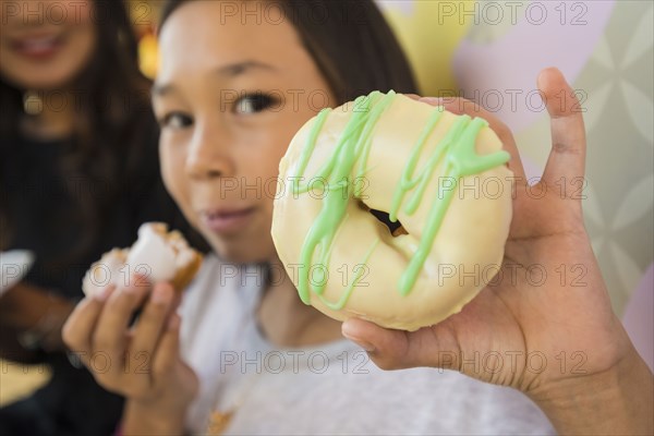 Close up of girl holding donut in bakery