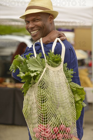 African American man carrying bag of vegetables