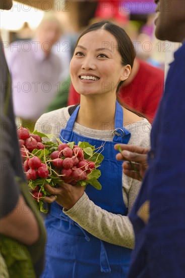 Clerk holding produce at farmers market