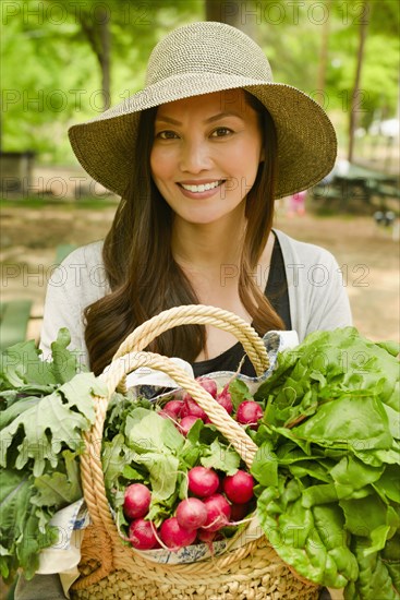 Asian woman carrying basket of produce