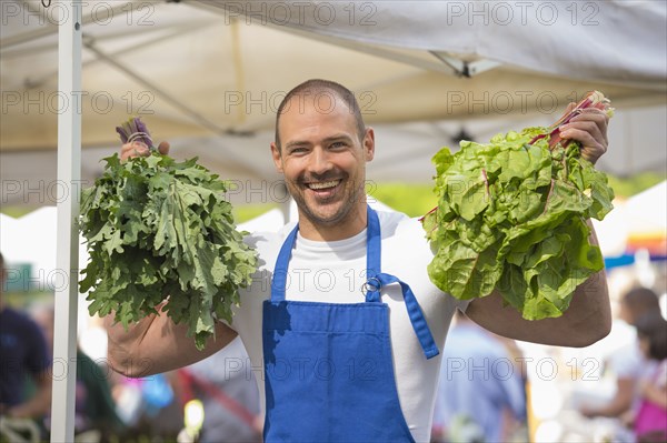Caucasian clerk holding bunches of lettuce