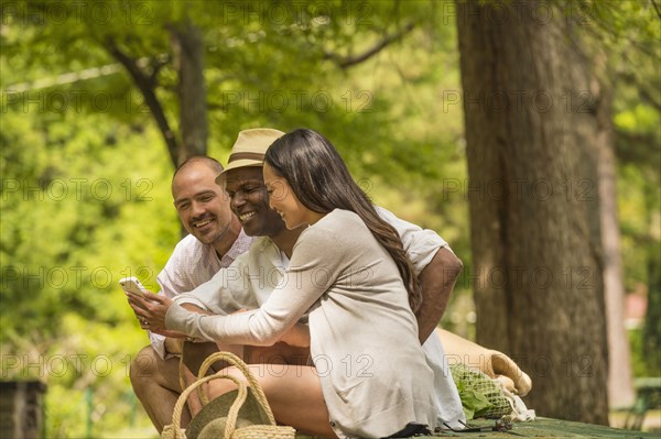 Friends using cell phone on picnic table