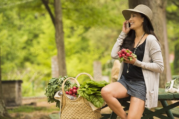 Asian woman talking on cell phone on picnic table