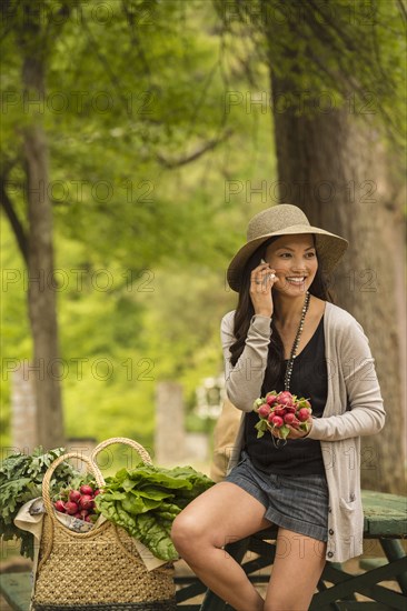 Asian woman talking on cell phone on picnic table