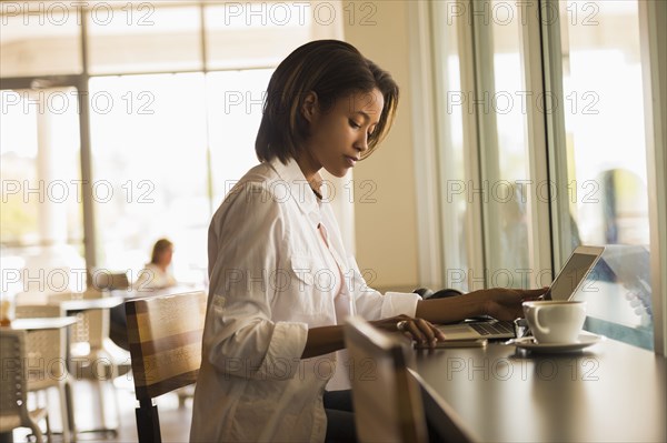 African American woman using laptop in cafe