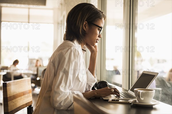 African American woman using laptop in cafe