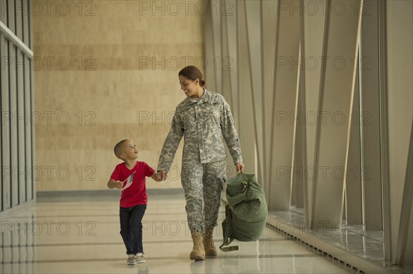 African American soldier and son walking in airport