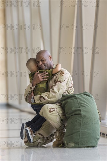 African American soldier hugging son in airport