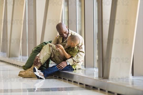 African American soldier and son talking in airport