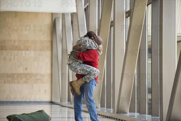 African American soldier hugging husband in airport