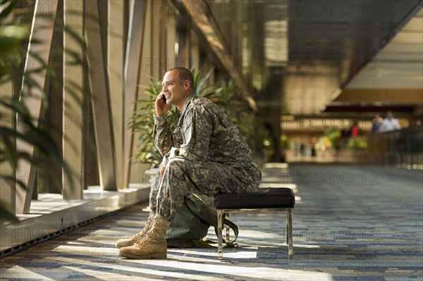 Caucasian soldier talking on cell phone in airport