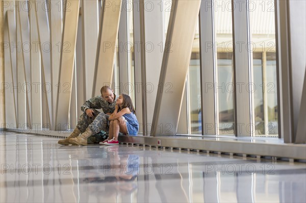 Returning soldier talking to daughter in airport
