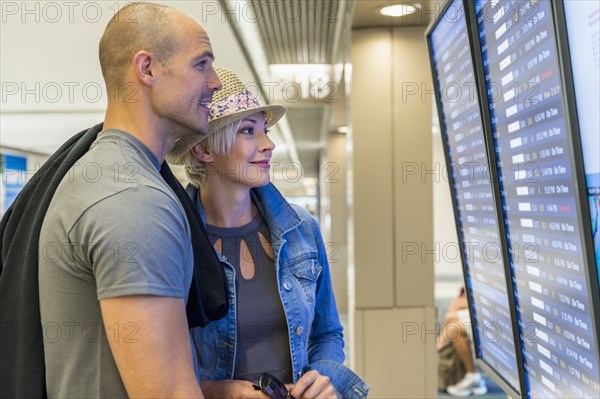 Caucasian couple reading arrivals and departures in airport