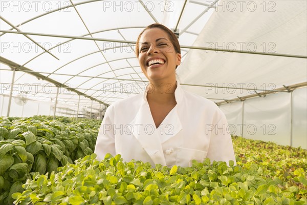 Black chef standing in greenhouse holding tray of plants