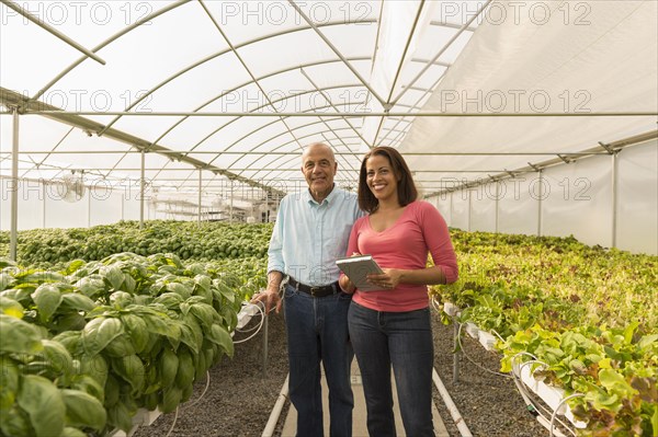 Couple holding clipboard standing in greenhouse