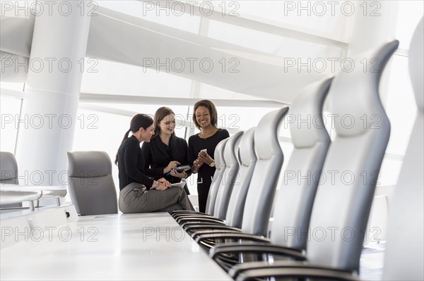 Businesswomen using cell phone in conference room
